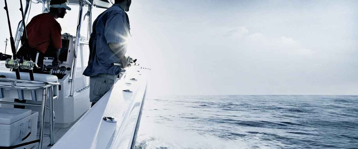 Shot of two men driving and fishing from speedboat, Miami, USA, wearing fishing gear